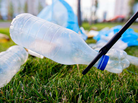 Tongs for cleaning garbage. Lawn cleaning from plastic bottles. Close-upの写真素材