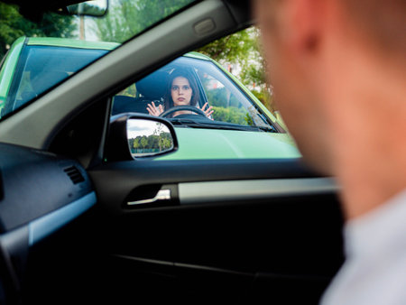 The frustrated and frightened girl looks at the driver of the car she crashed into. Crossroad...