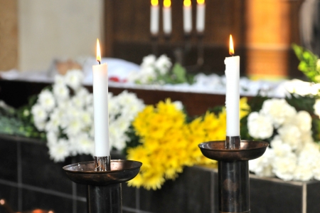 A burning candle with a coffin and a flower-arrangementの写真素材