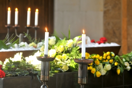 A burning candle with a coffin and a flower-arrangementの写真素材