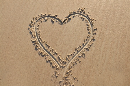 A heart shape drawn in the sandの写真素材
