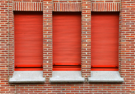 three windows with red roller shutterの写真素材