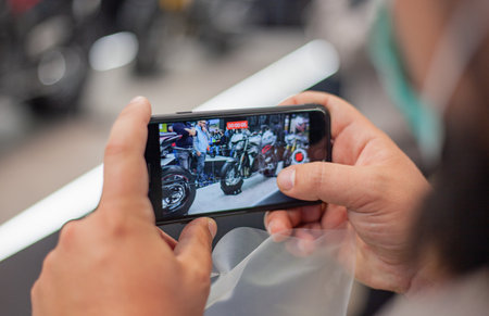 Fiera Milano, november 2021. A man photographs a motorcycle on a mobile phone at a motorcycle exhibition EICMAのeditorial素材