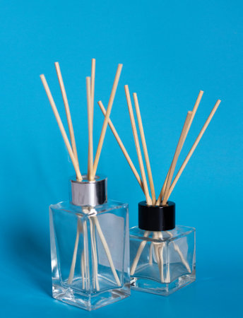 two bottles for home perfumes with incense sticks on a blue backgroundの写真素材