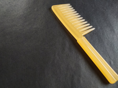 Wide tooth hair comb isolated on black background.の写真素材
