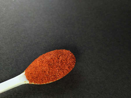 Spoonful red chilli powder isolated on black background.の写真素材