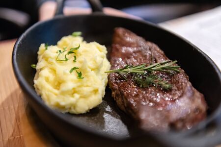 Beef steak with potatoes in a pan. Rosemary on fried meat.の写真素材