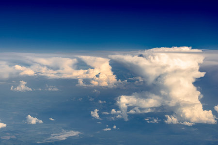 Clouds from the porthole. Cascades of white clouds in a blue sky haze. The view from the plane.