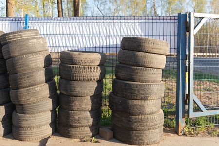 Tires. Car wheels are stacked in a column. Old tires at the service station.の写真素材