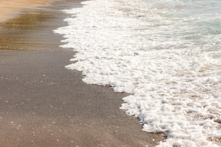 Mediterranean surf. Small waves roll on the shore. Sea foam on the beach.