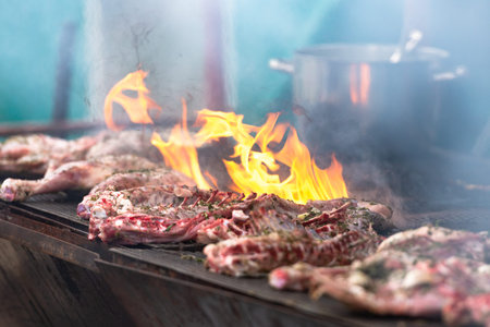 Cooking delicious meat. Italian chefs prepare treats for a large company. Large pieces of grilled meat.の写真素材
