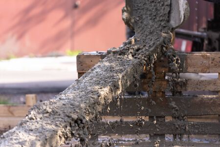 The concrete is poured on a wooden tray. As it merges down, the concrete splashes a lot of spray.の写真素材