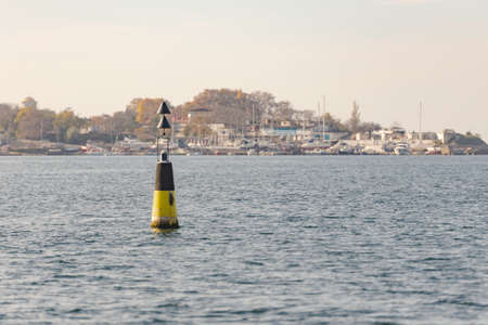 Sea sign on the buoy indicating the fairway. Black and yellow sign of the cardinal directionsの写真素材