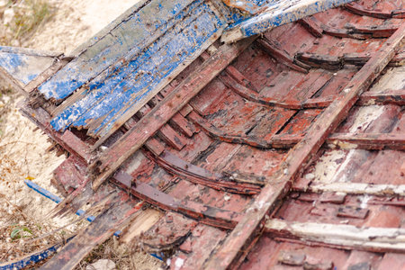 Remains of an old wooden boat. The bow of the wooden boat is stuck in the coastal rocks.