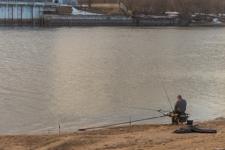 Moscow. Russia. March 2021. A fisher man catches fish with several fishing rods in Kapotnya Park.のeditorial素材