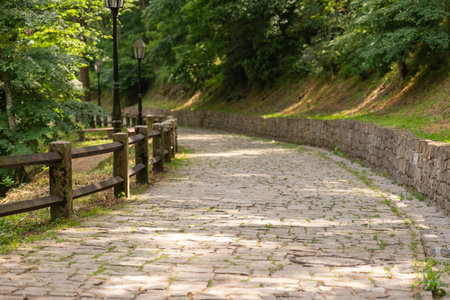 A stone paved path leading down from the mountain. Stone path and wall. Wooden fence made of thick beams.の写真素材