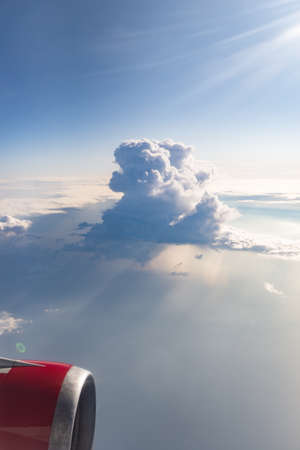 Photo from the window of the plane. A beautiful cloud and the sun's rays through it. Airplane engine on the background of a beautiful cloud.の写真素材