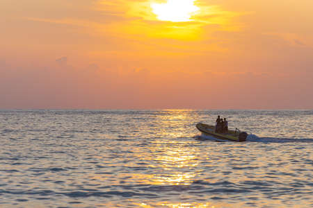 motor boat at sea. A yellow rubber boat cleaves the calm sea in the sunset light.の写真素材