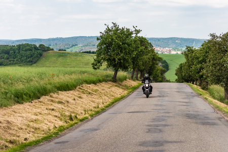 Road through the Czech Republic. Moravian fields and a lone motorcyclist.の写真素材