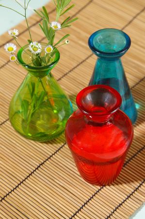 Three bright jars on a bamboo mat, holding oil, salt and herbs.の写真素材