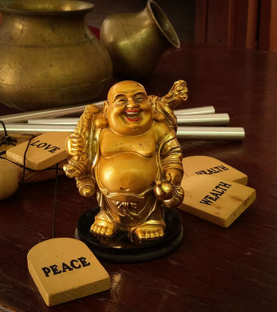 Laughing Buddha idol with pots in the background. The idol is a prestigious symbol in Buddhism.の写真素材