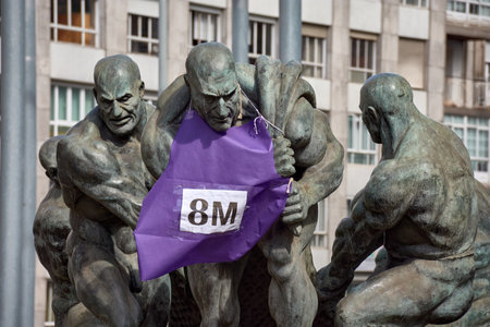 Vigo, Pontevedra, Spain; March,08,2022; The sculpture of the Rowers in Vigo with a purple sign celebrating Working Women's Dayのeditorial素材