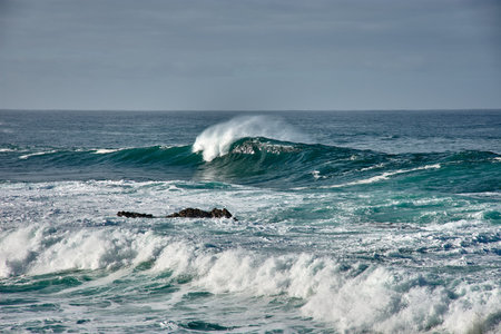 Waves break at Cabo Silleiro on the Baiona breakwater on the coast of Galicia, Spain