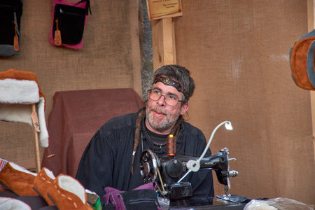 Baiona, Pontevedra, Galicia, Spain; March, 04,2023; an artisan shoemaker sewing and with glasses at...