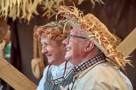 Baiona, Pontevedra, Galicia, Spain; March, 04,2023; A man and another woman craftsman laugh at the Arribada festival, one with a straw hat and flowers and the woman with a flower headbandのeditorial素材