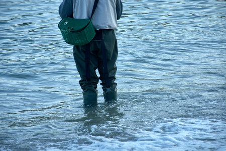the traditional attire of a fisherman wading in the water, equipped with sturdy boots and a basket...