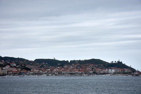 Charming coastal village of Bayona, located in Pontevedra, Spain, as seen from Montelourido. The photograph shows the village's unique blend of modern apartments and traditional houses, nestled against a green hillside.の写真素材