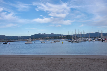 A serene scene from Barbeira Beach in Bayona, Pontevedra, Spain. The calm waters of the bay are...