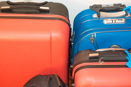 Three suitcases stand ready, perfectly packed and aligned, symbolizing the beginning of an exciting new adventure. The bright red and blue colors of the luggage capture the spirit of travel and exploration. These bags, equipped with sturdy handles and secure locks, are ideal companions for any journey, whether it be a weekend getaway or a long international trip.の写真素材
