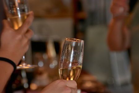 A close-up of hands holding champagne glasses during a toast, capturing a celebratory moment. Ideal for holidays, parties, and friendship themes.の写真素材