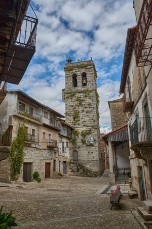 an evocative cobblestone alley in the village of Mogarraz, Salamanca, flanked by traditional houses with wooden balconies and stone walls. A distinctive element is the photographic portraits of residents adorning the facades, a project that pays homage to the town's identity and history. The linear composition guides the eye through the street, revealing the unique fusion of architectural heritage and cultural expression, ideal for publications on rural tourism, urban art, local history, or the authenticity of Spanish villagesの写真素材