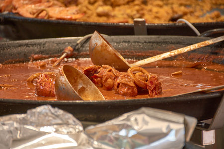 A freshly cooked rice dish It is presented in the foreground on a metal tray at an open-air market...