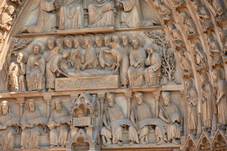 Close-ups of the facade of Notre Dame in Paris reveal carved stone sculptures depicting religious figures, kings, and saints with crowns, robes, and symbolic objects. Framed by Gothic arches and pinnacles, these medieval works convey solemnity, devotion, and artistic mastery. Ideal for illustrating themes of heritage, sacred art, Christian history, and European architecture.の写真素材