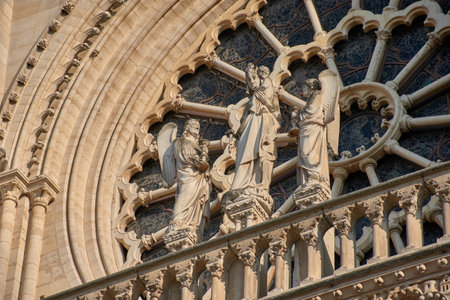 Close-ups of the facade of Notre Dame in Paris reveal carved stone sculptures depicting religious figures, kings, and saints with crowns, robes, and symbolic objects. Framed by Gothic arches and pinnacles, these medieval works convey solemnity, devotion, and artistic mastery. Ideal for illustrating themes of heritage, sacred art, Christian history, and European architecture.の写真素材