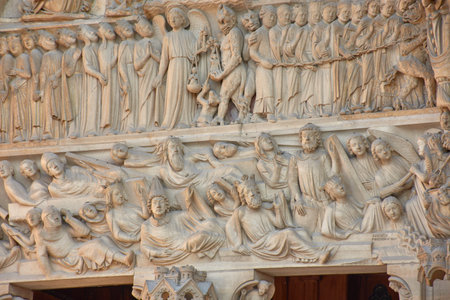 Close-ups of the facade of Notre Dame in Paris reveal carved stone sculptures depicting religious figures, kings, and saints with crowns, robes, and symbolic objects. Framed by Gothic arches and pinnacles, these medieval works convey solemnity, devotion, and artistic mastery. Ideal for illustrating themes of heritage, sacred art, Christian history, and European architecture.の写真素材