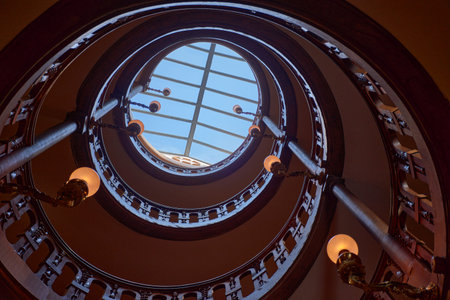 The spiral staircase at Fontainebleau Palace spirals upward with ornate railings and a circular...