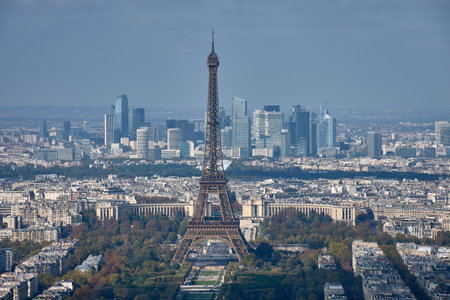 From the top of the Montparnasse Tower, a panoramic view of Paris unfolds, with the Eiffel Tower majestically centered in the frame. In the background, the skyscrapers of the La Defense district contrast with the classic architecture of the historic center, creating a visual composition that reflects the duality between tradition and modernity. Ideal for tourism, editorial, and cultural content related to urban planning, Parisian heritage, and travel photographyの写真素材