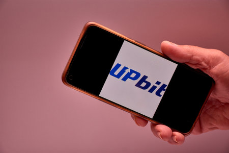Vigo, Spain, November 30, 2025.A human hand holds a smartphone whose screen displays the logo of Upbit, South Korea's largest cryptocurrency exchange by trading volume. The composition is clear, modern, and functional, ideal for content about fintech, bloのeditorial素材