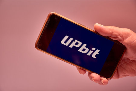 Vigo, Spain, November 30, 2025.A human hand holds a smartphone whose screen displays the logo of Upbit, South Korea's largest cryptocurrency exchange by trading volume. The composition is clear, modern, and functional, ideal for content about fintech, bloのeditorial素材