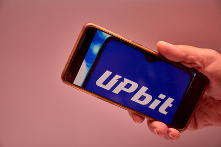 Vigo, Spain, November 30, 2025.A human hand holds a smartphone whose screen displays the logo of Upbit, South Korea's largest cryptocurrency exchange by trading volume. The composition is clear, modern, and functional, ideal for content about fintech, bloのeditorial素材