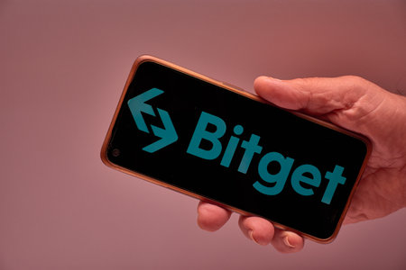 Vigo, Spain, November 30, 2025.A human hand holds a smartphone whose screen displays the Bitget logo, a leading global cryptocurrency and Web3 exchange platform with over 100 million users. The background and clean design reinforce the technological and cのeditorial素材