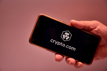 Vigo, Spain, November 30, 2025.A human hand holds a smartphone whose screen displays the logo of Crypto.com, an international cryptocurrency platform headquartered in Singapore with a presence in over 90 countries. The clean design reinforces the technoloのeditorial素材
