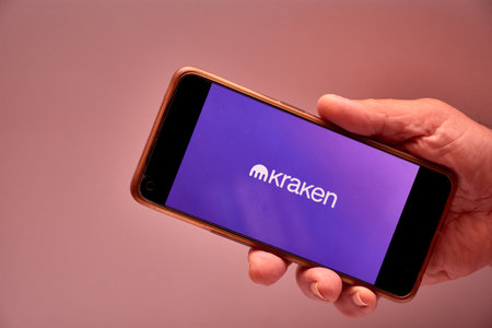 Vigo, Spain, November 30, 2025.A human hand holds a smartphone whose screen displays the logo of Kraken, a US-based cryptocurrency exchange platform. The minimalist design reinforces the technological and corporate aesthetic, conveying trust, efficiency, のeditorial素材