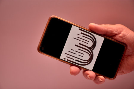 Vigo, Spain, November 30, 2025.A human hand holds a smartphone whose screen displays the BitMart logo, a centralized cryptocurrency exchange platform with over 9 million users worldwide. The clean design reinforces the technological and corporate aesthetiのeditorial素材