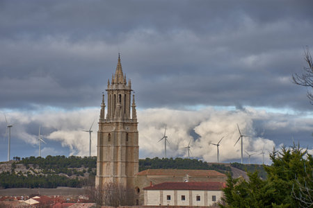 The bell tower of the Collegiate Church of San Miguel rises above the rooftops of Ampudia, standing...