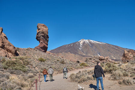 Teide, Tenerife, January 13, 2026, A group of visitors walks along the trails of ocher sand and basalt rocks that extend at the foot of the imposing Mount Teide. The composition uses the contrast between the earthy tones of the volcanic desert and the vibのeditorial素材